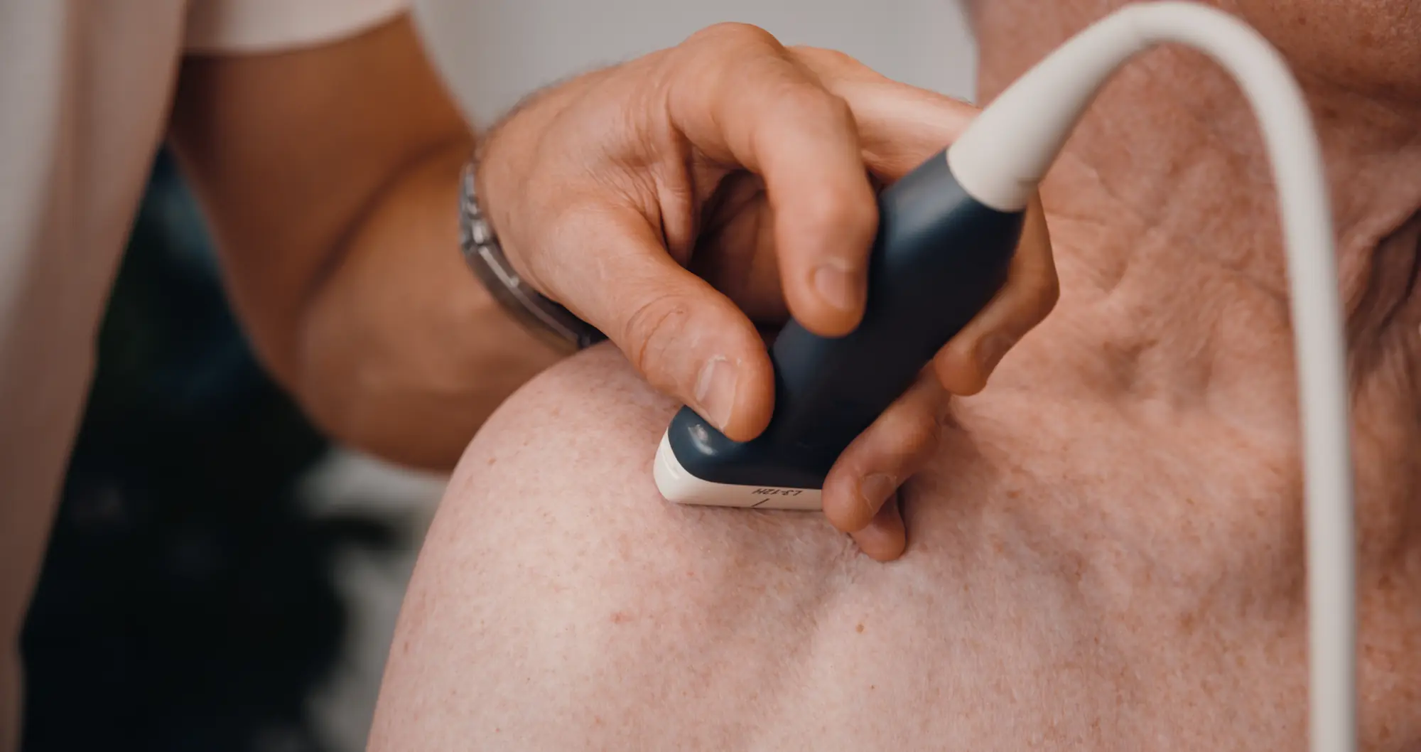 Ultraschallsonde an der Schulter eines Patienten